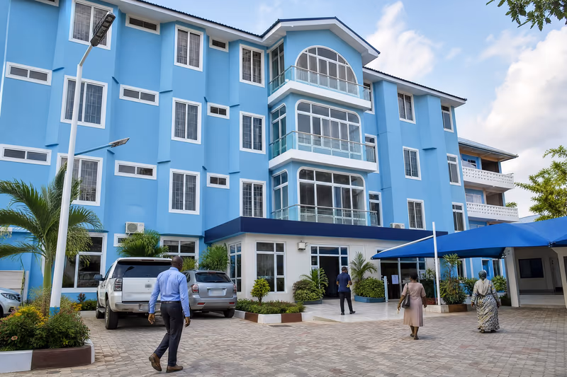 Illustrative scene: The sky-blue multi-storey main building seen from its paved courtyard, with a navy canopy over the entrance.